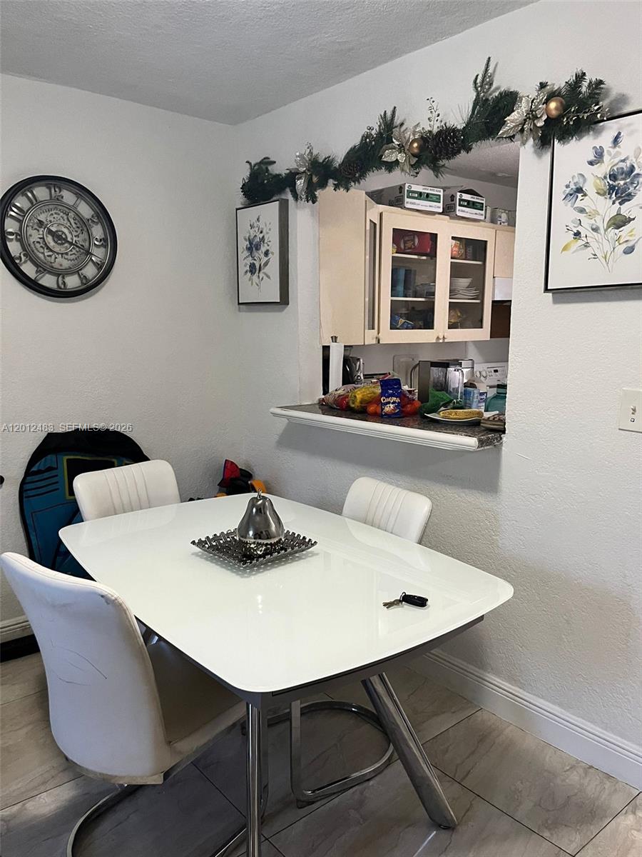 A dining area features a white table, four chairs, a wall clock, and a kitchen pass-through — 652 NW 3rd St # 103, Miami FL 33128, MIAMI, FL