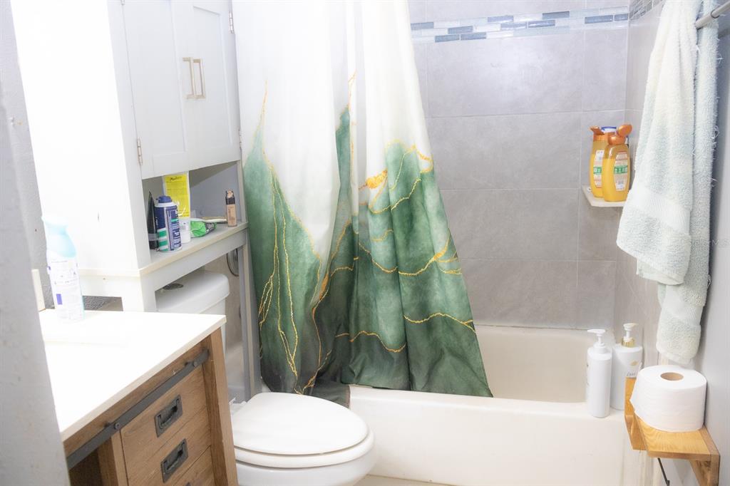 A bathroom features a vanity, a toilet, and a bathtub with a green patterned shower curtain — 924 LAKE DESTINY ROAD UNIT D, ALTAMONTE SPRINGS, FL