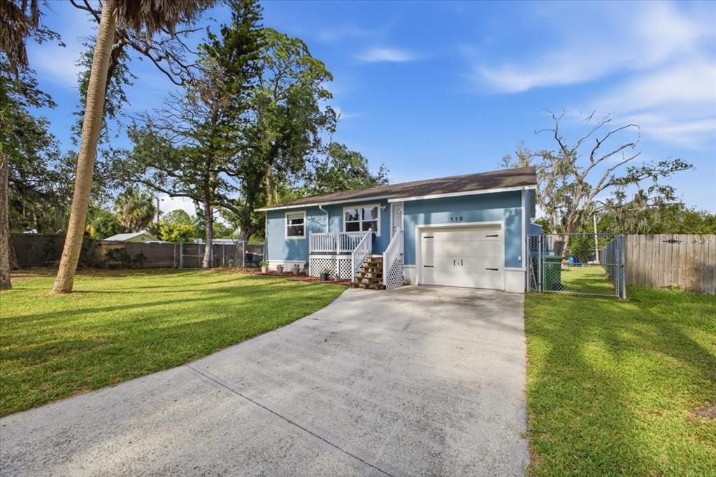 A blue single-story house with a white garage door and a concrete driveway — 115 BROWN ST, BRADENTON, FL