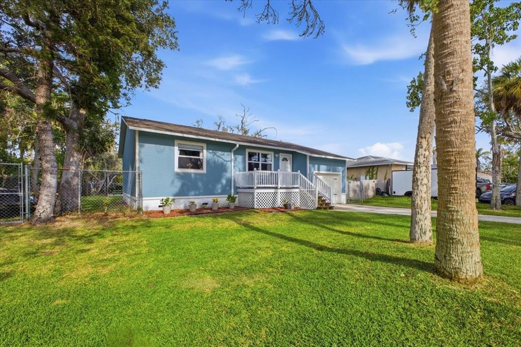 A blue single-story house with a white front deck and a grassy front yard — 115 BROWN ST, BRADENTON, FL