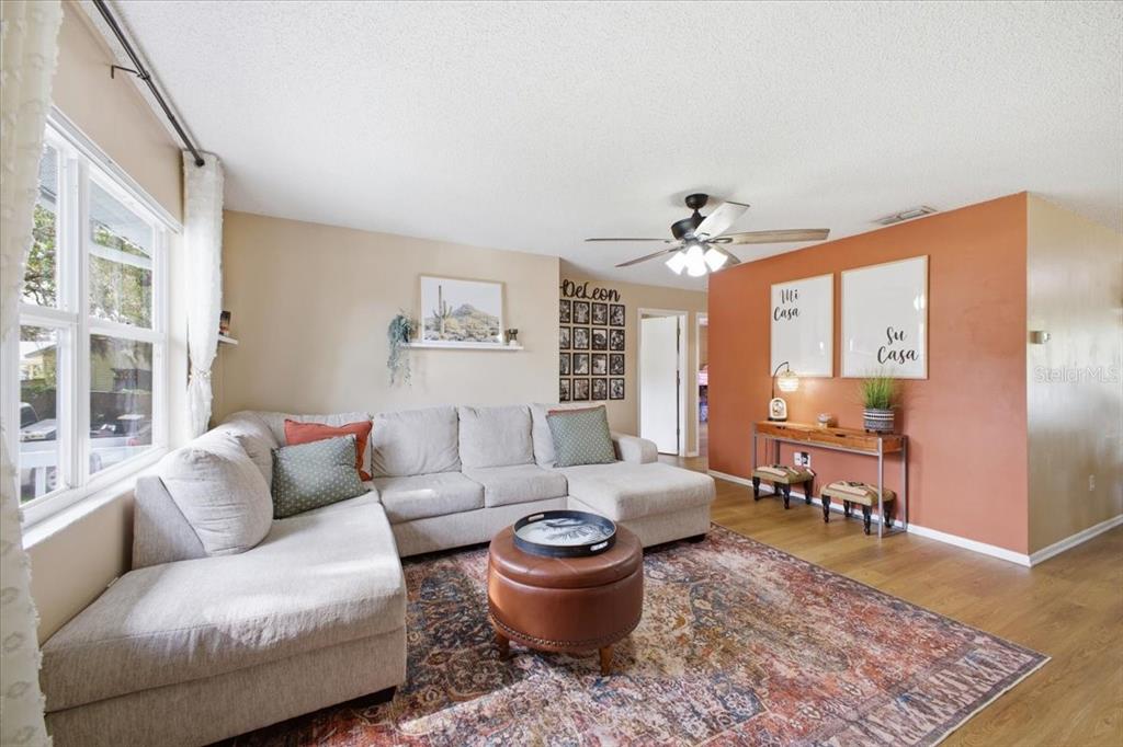 A living room features a sectional sofa, a round ottoman, and an orange accent wall — 115 BROWN ST, BRADENTON, FL