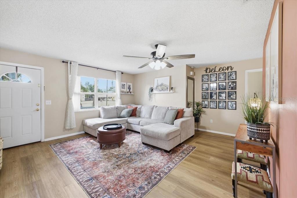 A living room features a sectional sofa, a patterned rug, and a photo gallery wall — 115 BROWN ST, BRADENTON, FL