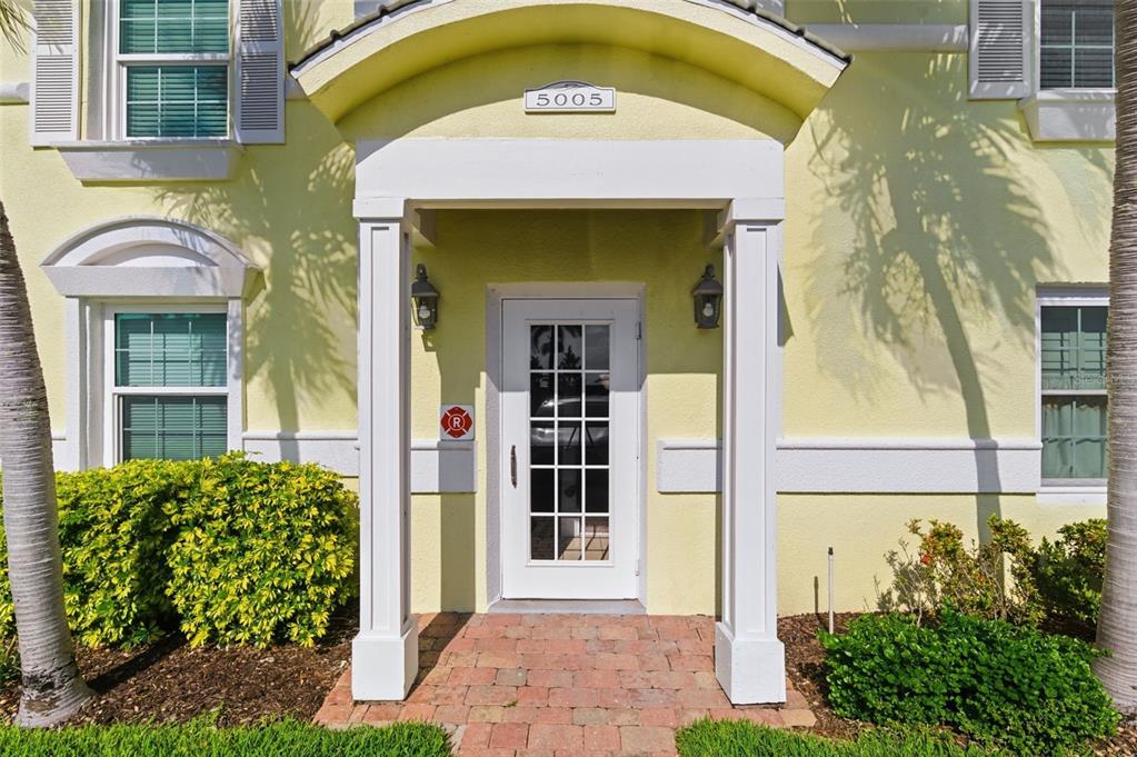 A yellow building exterior features a white front door under a covered entryway — 5005 COQUINA KEY DRIVE SE UNIT E, ST PETERSBURG, FL