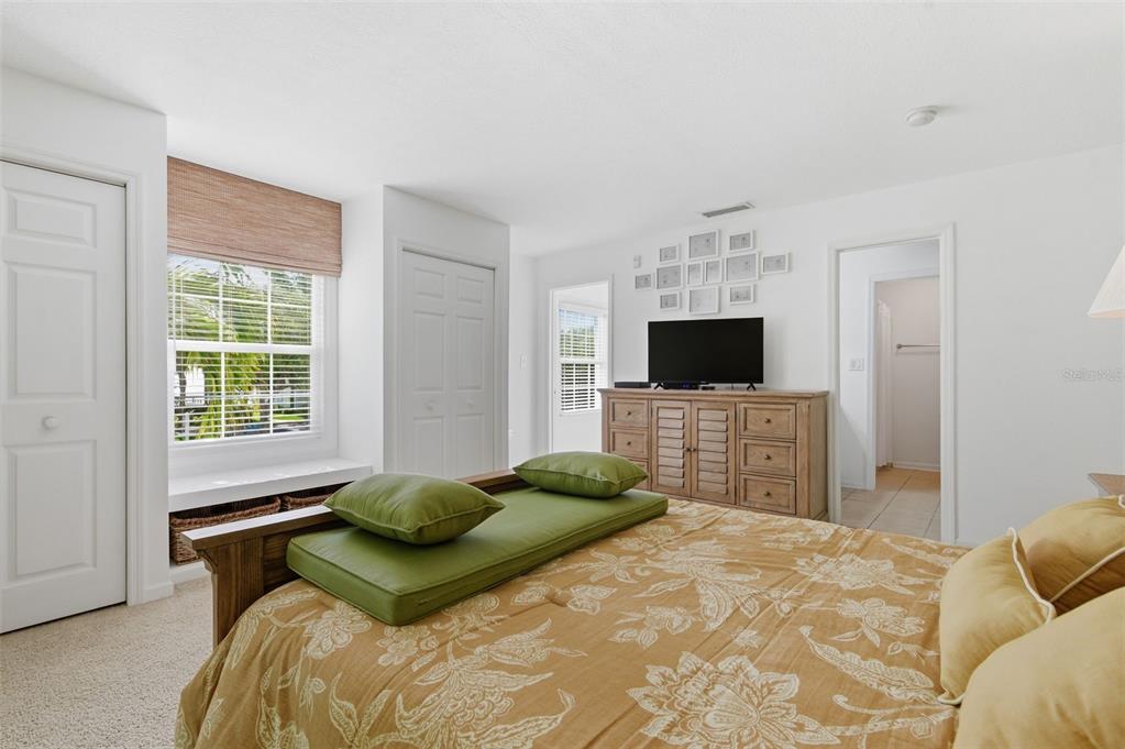 A bedroom features a bed with a green cushion, a wooden dresser, and a window — 5005 COQUINA KEY DRIVE SE UNIT E, ST PETERSBURG, FL