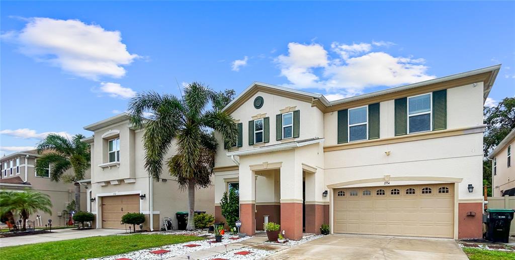 A two-story suburban house with a tan stucco exterior and a two-car garage — 2754 ARBOR TRAIL WAY, ORLANDO, FL