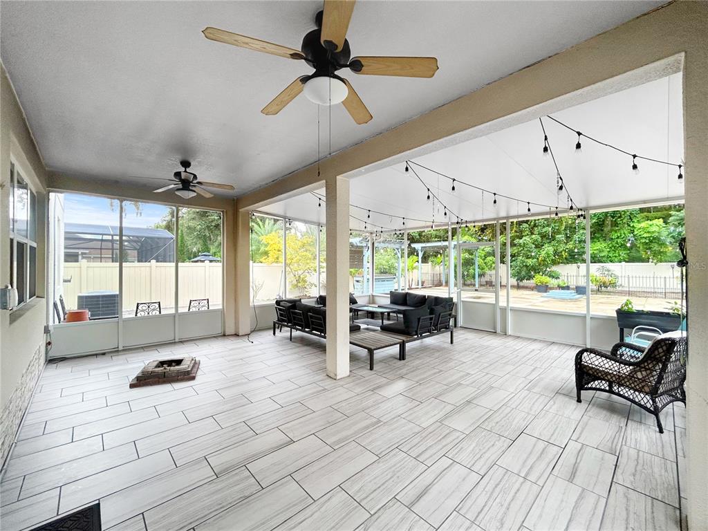 A covered patio features light wood-look tile flooring, two ceiling fans, and outdoor furniture — 2754 ARBOR TRAIL WAY, ORLANDO, FL