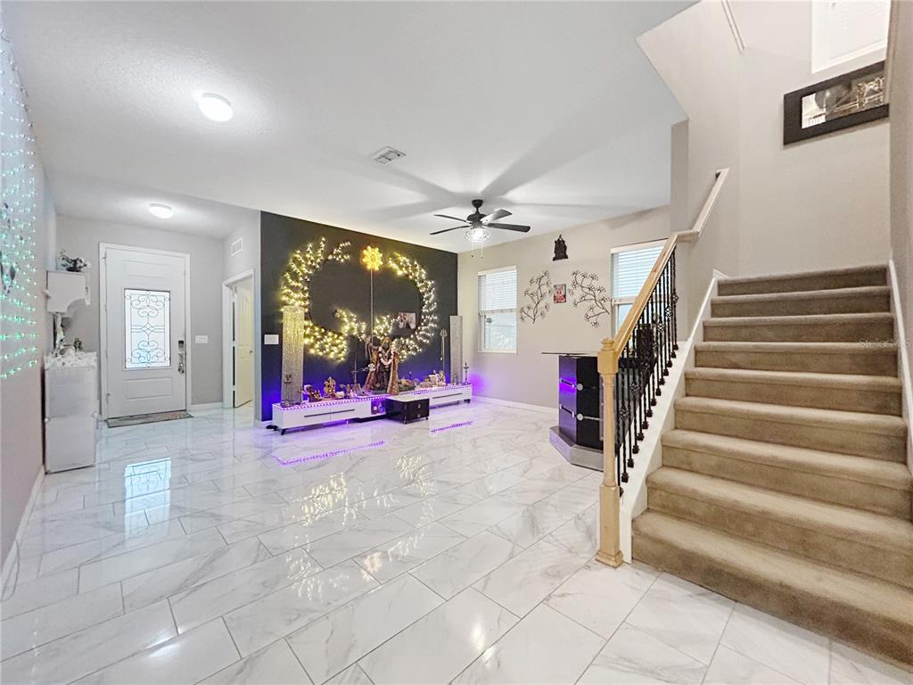 A foyer with white marble-look tile flooring, a staircase, and a decorated wall display — 2754 ARBOR TRAIL WAY, ORLANDO, FL