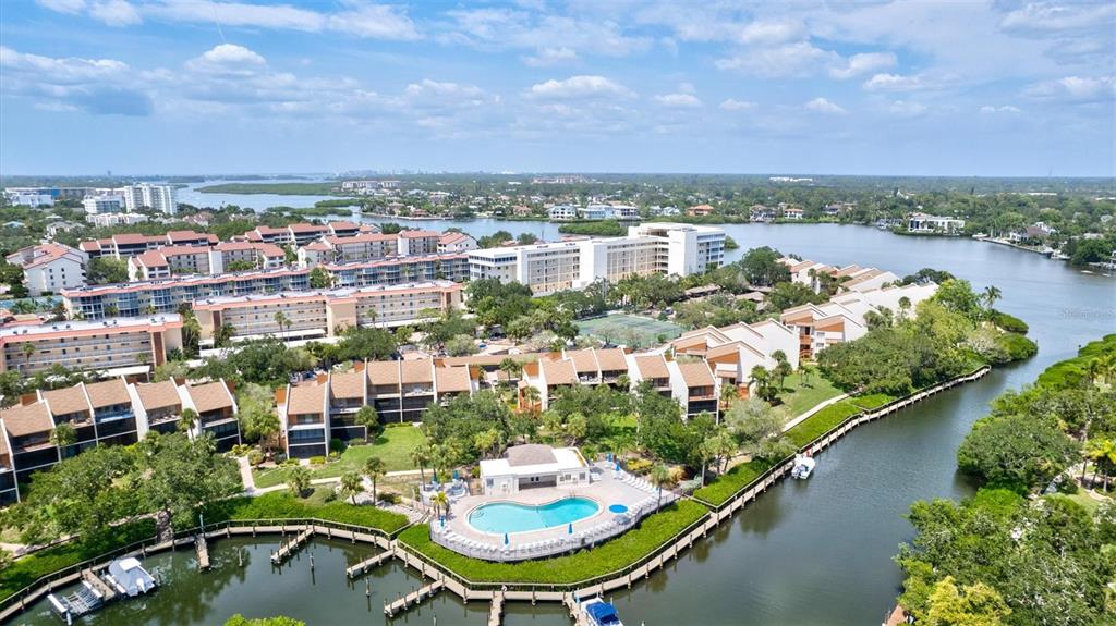 An aerial view shows a waterfront condominium complex with a pool and boat docks — 1700 COVE II PLACE UNIT 310, SARASOTA, FL
