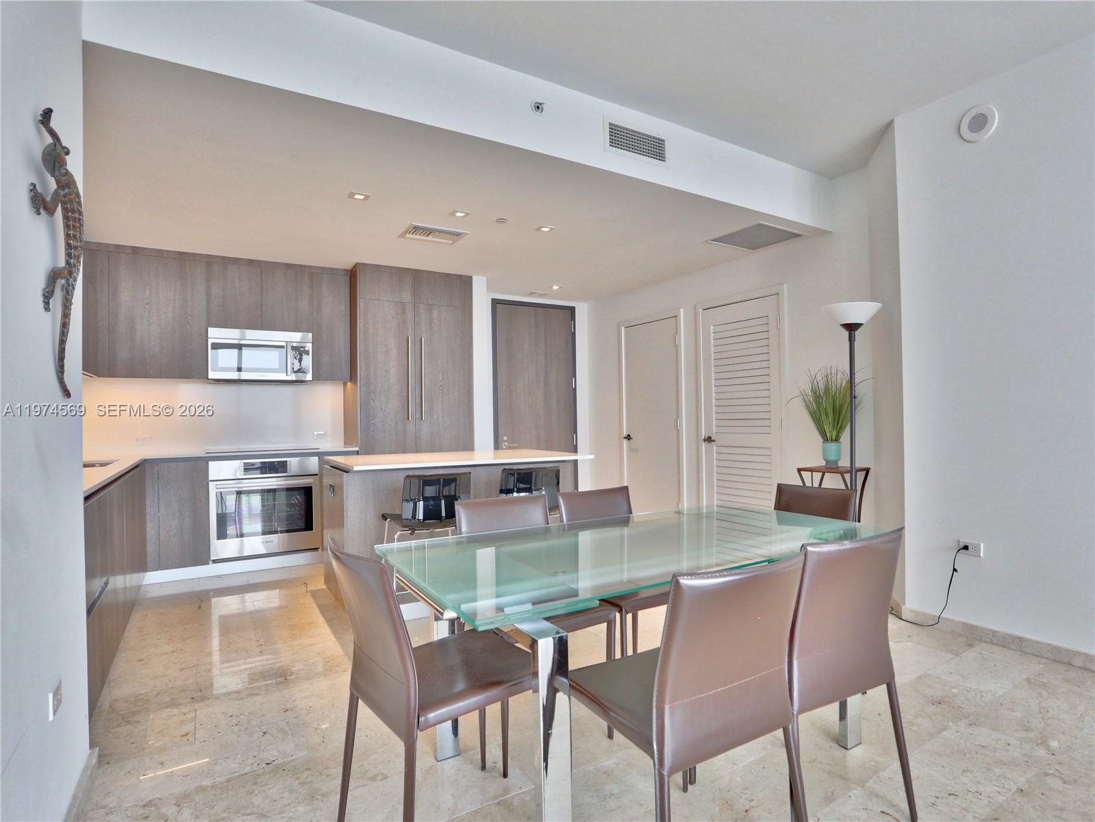 A modern kitchen with wood cabinets and a glass-topped dining table on marble floors — 88 SW 7th St # 3805, Miami FL 33130, MIAMI, FL