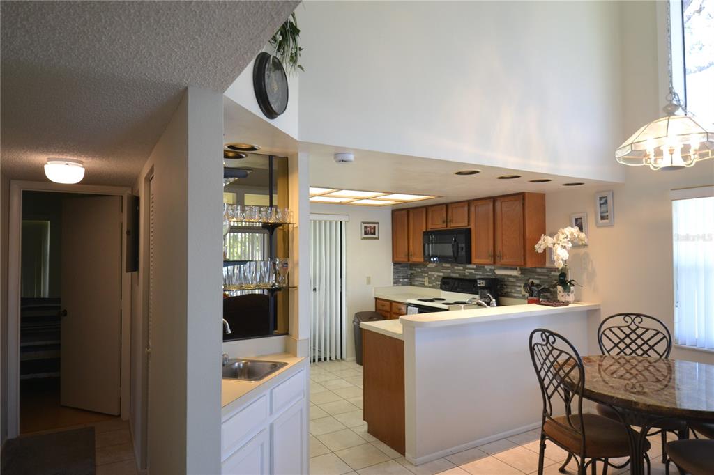 A kitchen with wood cabinets and a breakfast bar overlooks a dining area — 336 WOODLAKE WYNDE, OLDSMAR, FL