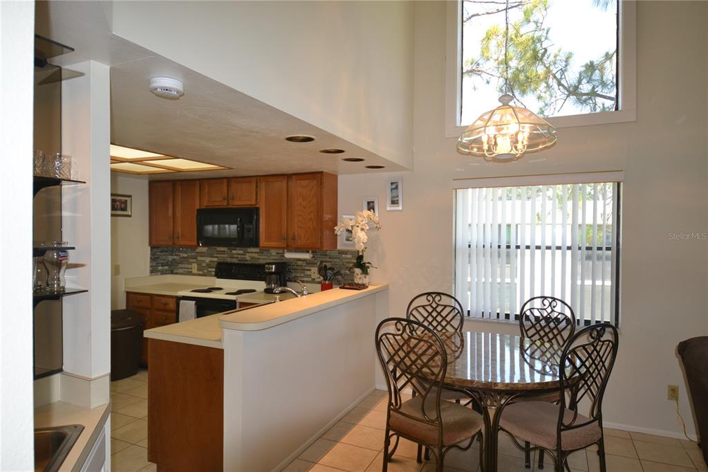 A kitchen with wood cabinets and a dining area with a table and chairs — 336 WOODLAKE WYNDE, OLDSMAR, FL