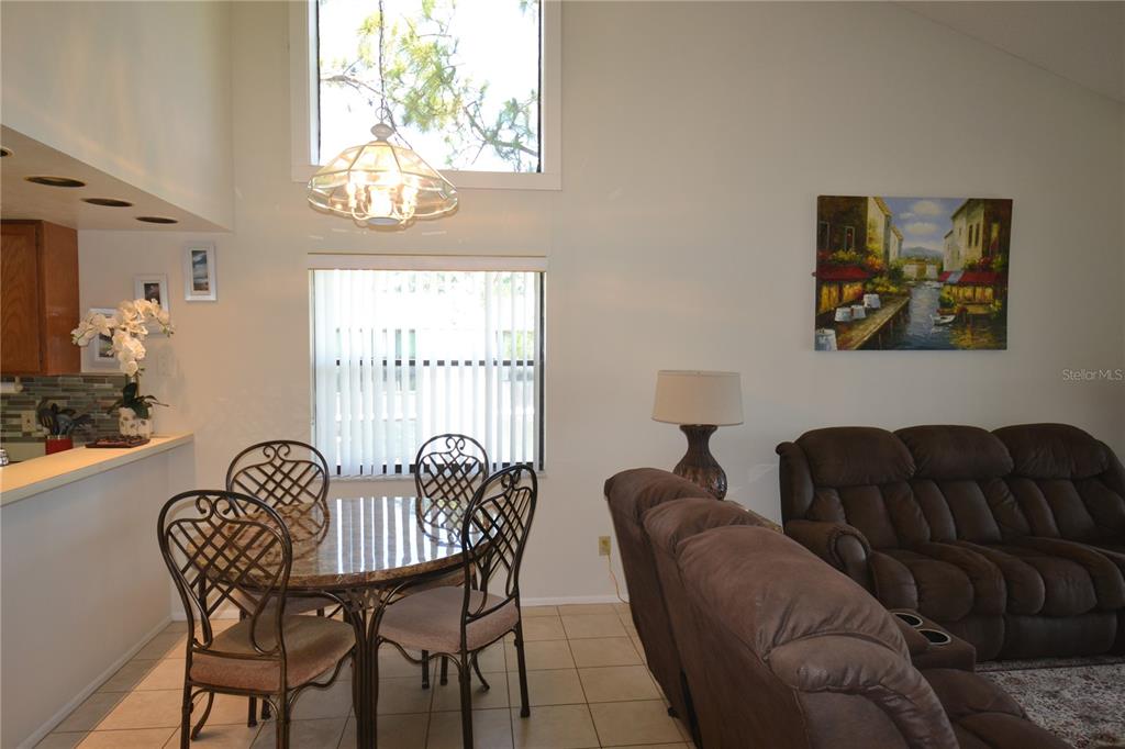 A dining area with a glass-topped table and chairs sits adjacent to a living room — 336 WOODLAKE WYNDE, OLDSMAR, FL