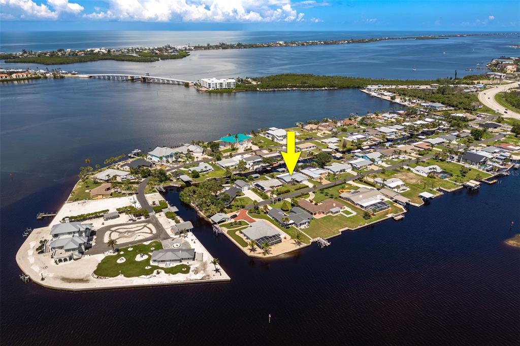 An aerial view shows a waterfront residential neighborhood with a yellow arrow pointing to a house — 1464 DEER CREEK DRIVE, ENGLEWOOD, FL