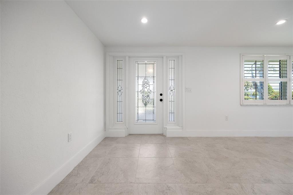 A bright entryway features white walls, light-colored tile flooring, and a decorative glass front door — 1464 DEER CREEK DRIVE, ENGLEWOOD, FL