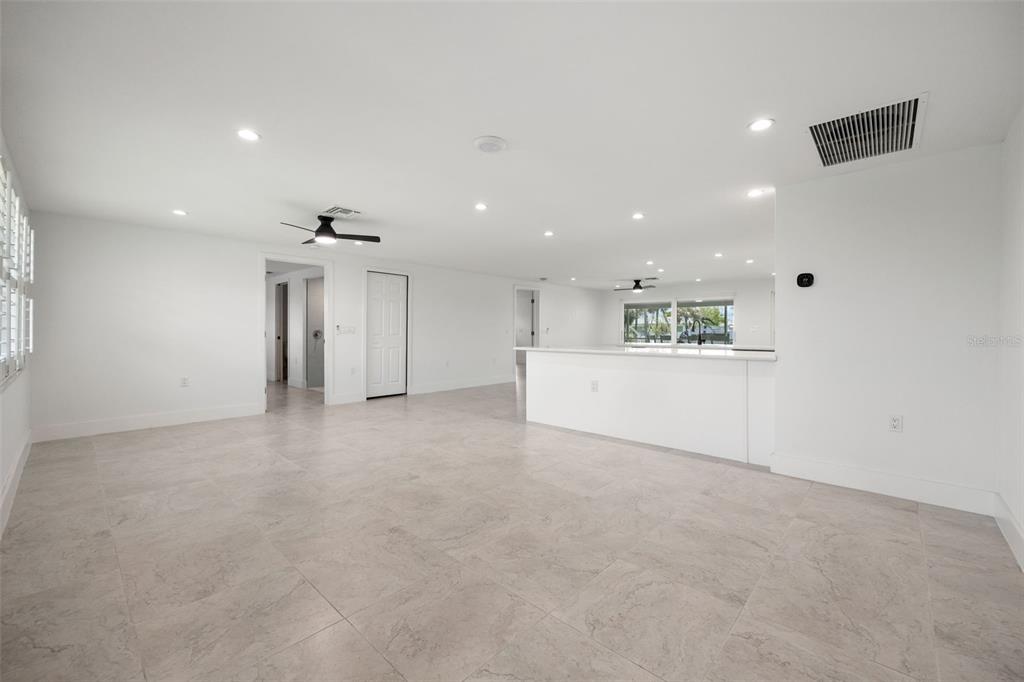 An open-concept living area features white walls, tile flooring, a kitchen island, and recessed lighting — 1464 DEER CREEK DRIVE, ENGLEWOOD, FL