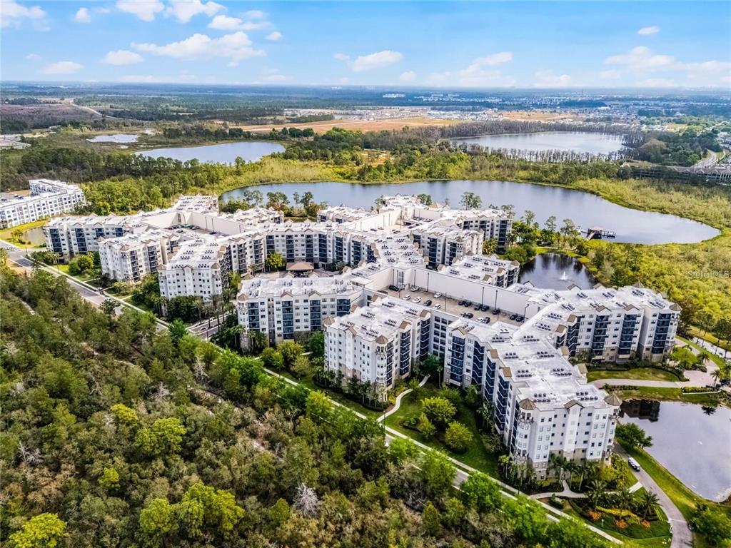 An aerial view of a large multi-story apartment complex surrounded by lakes and forest — 14501 GROVE RESORT AVE UNIT 3621, WINTER GARDEN, FL