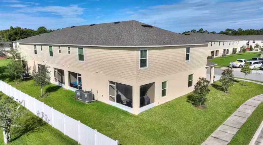 An aerial view of a two-story beige townhouse with a screened-in patio and backyard — 4877 CORAL CASTLE DRIVE, KISSIMMEE, FL