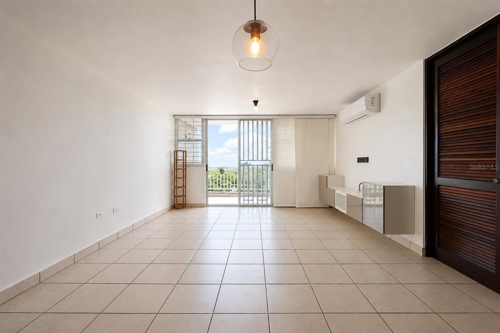 A bright, tiled living room features a glass sliding door leading to a balcony — Ave. Las Cumbres VISTAS DE SAN JUAN, SAN JUAN, PR