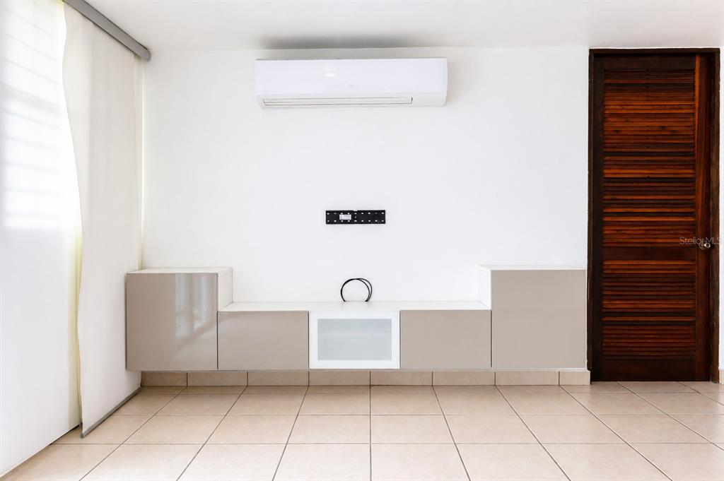 A room with tiled floors, a wall-mounted air conditioner, a media console, and a wooden door — Ave. Las Cumbres VISTAS DE SAN JUAN, SAN JUAN, PR