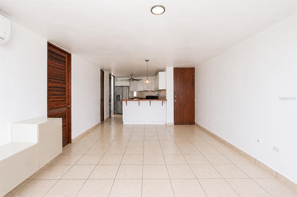 An open-concept living area features light tile flooring, white walls, and a kitchen with white cabinetry — Ave. Las Cumbres VISTAS DE SAN JUAN, SAN JUAN, PR
