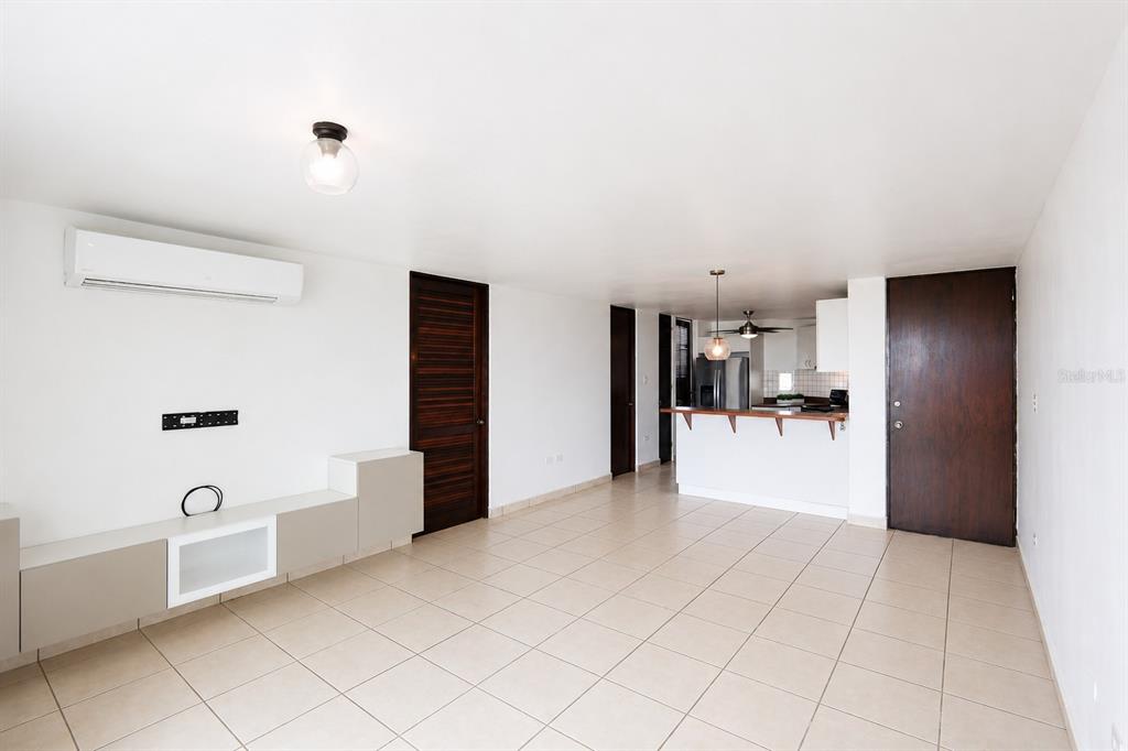 An open-concept living room features white walls, tile flooring, a built-in media console, and kitchen — Ave. Las Cumbres VISTAS DE SAN JUAN, SAN JUAN, PR