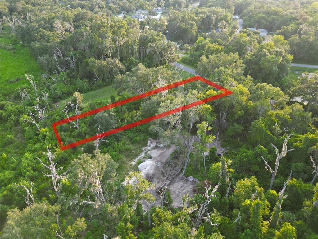 An aerial view shows a rectangular plot of land outlined in red amidst dense trees — 3418 E PERRY STREET, INVERNESS, FL