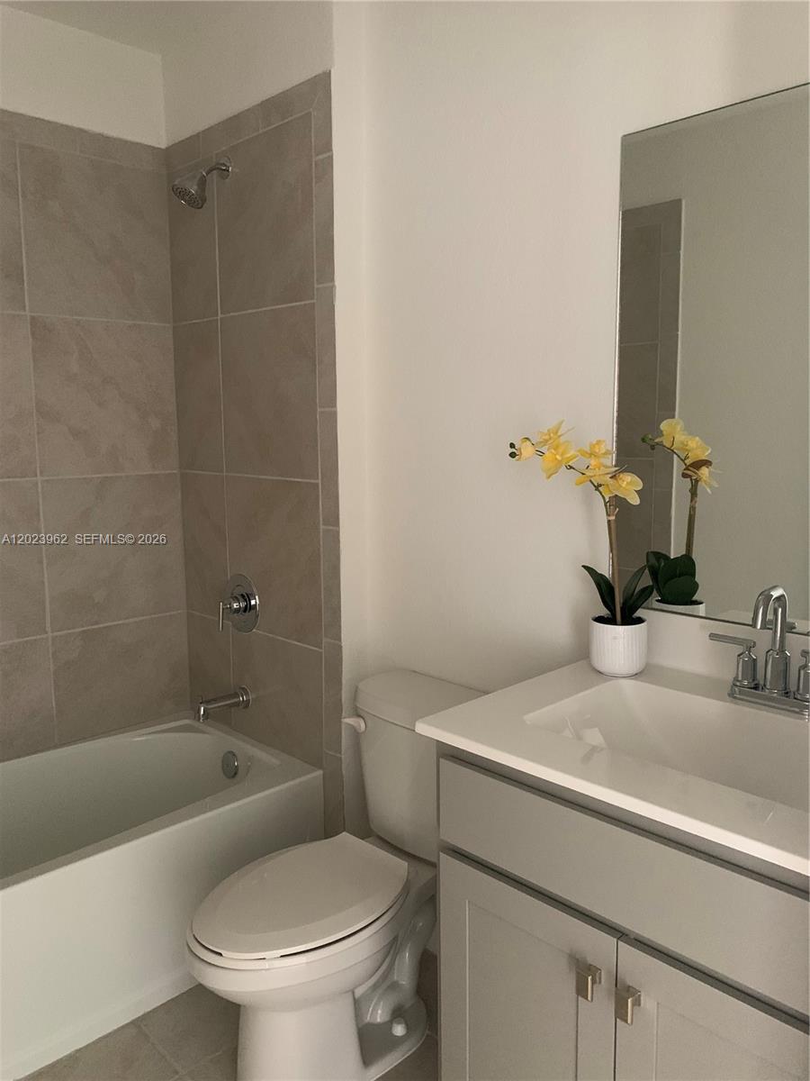 A bathroom features a light gray vanity, a white toilet, and a tiled shower-tub combination — 1068 SE 24th Ave, Homestead FL 33035, HOMESTEAD, FL