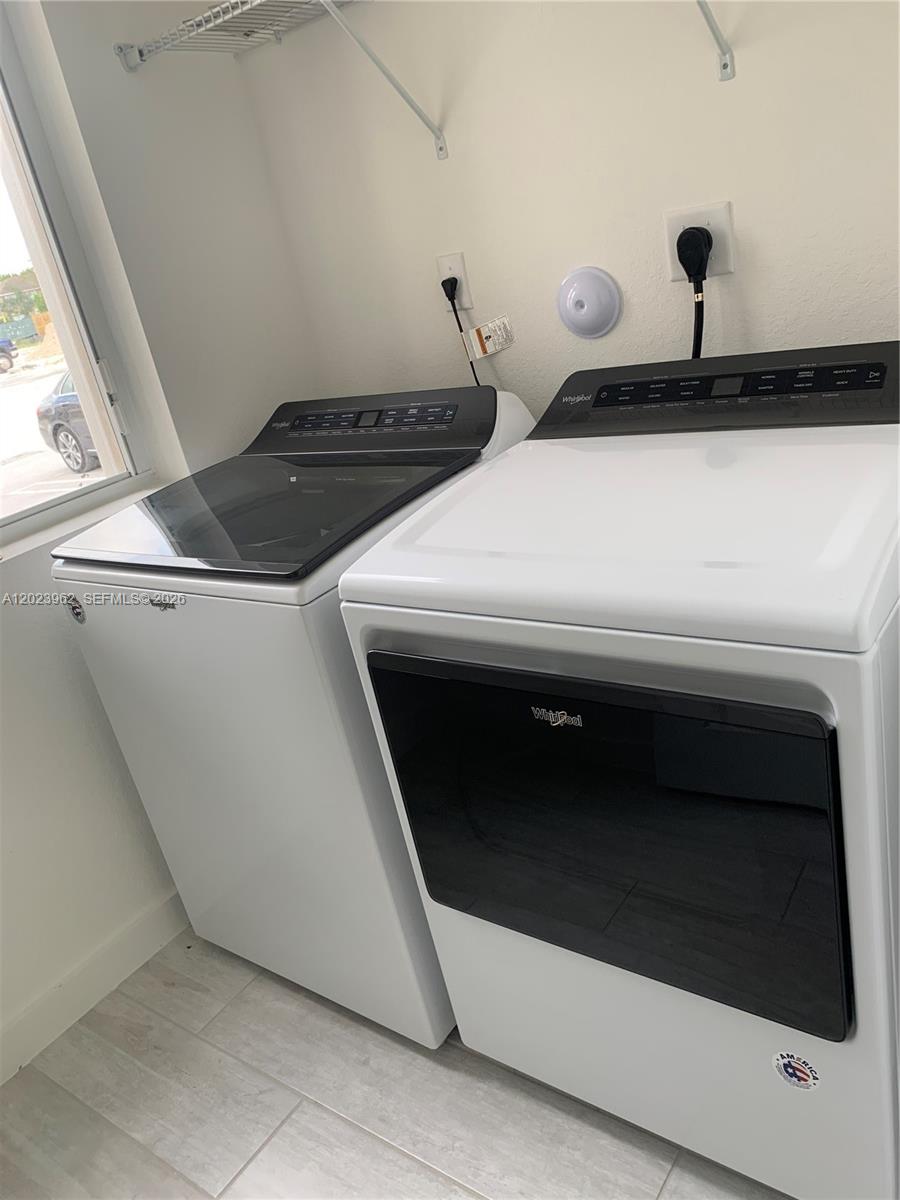 A laundry room features a white Whirlpool top-load washer and front-load dryer — 1068 SE 24th Ave, Homestead FL 33035, HOMESTEAD, FL