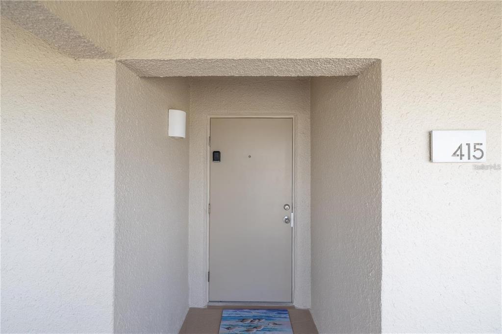 A beige exterior door with a number 415 sign sits in a recessed entryway — 4501 S ATLANTIC AVENUE UNIT 415, NEW SMYRNA BEACH, FL