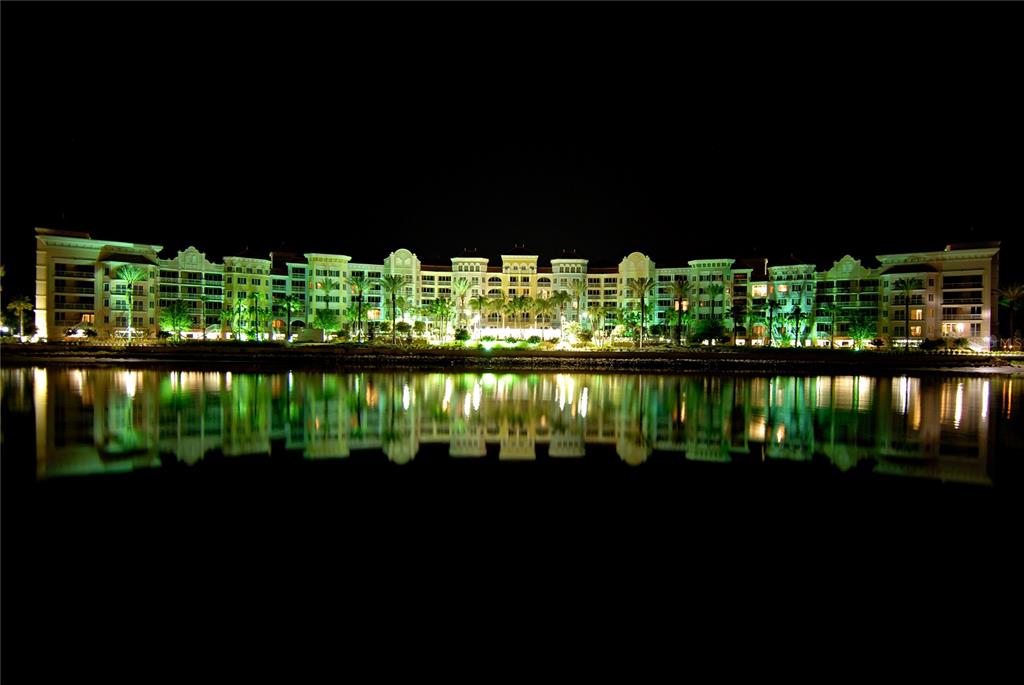 A large, multi-story resort building is illuminated at night, reflecting into the water in front — 102 YACHT HARBOR DRIVE UNIT 161, PALM COAST, FL