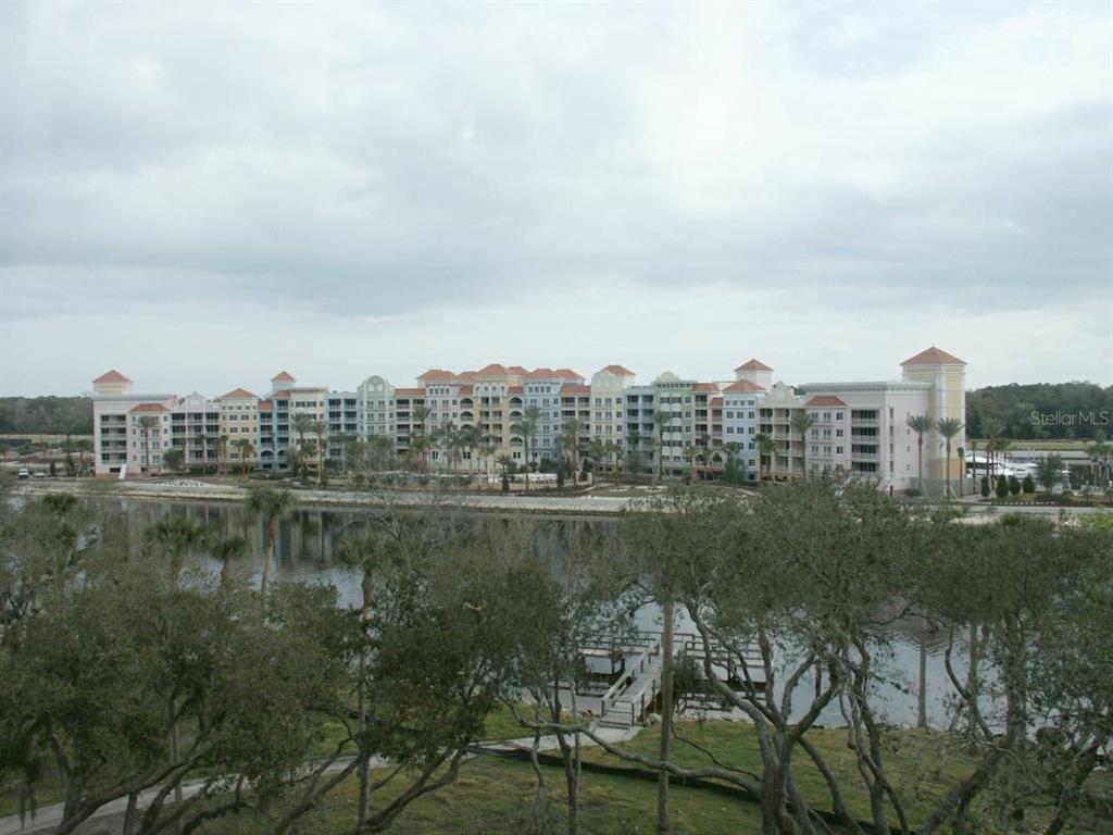 A large, multi-story apartment complex stands behind a body of water and trees — 102 YACHT HARBOR DRIVE UNIT 161, PALM COAST, FL