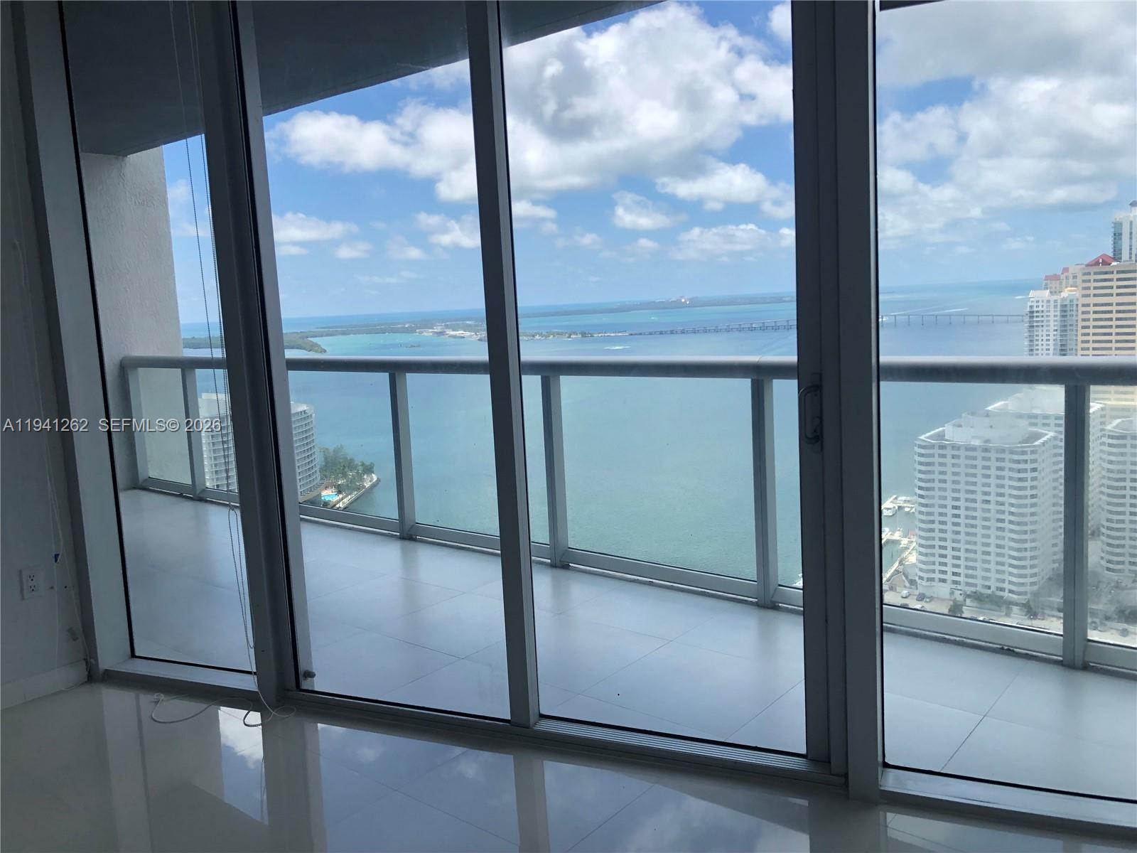 A view of the ocean and city skyline from a balcony through sliding glass doors — 495 Brickell Ave # 3507, Miami FL 33131, MIAMI, FL