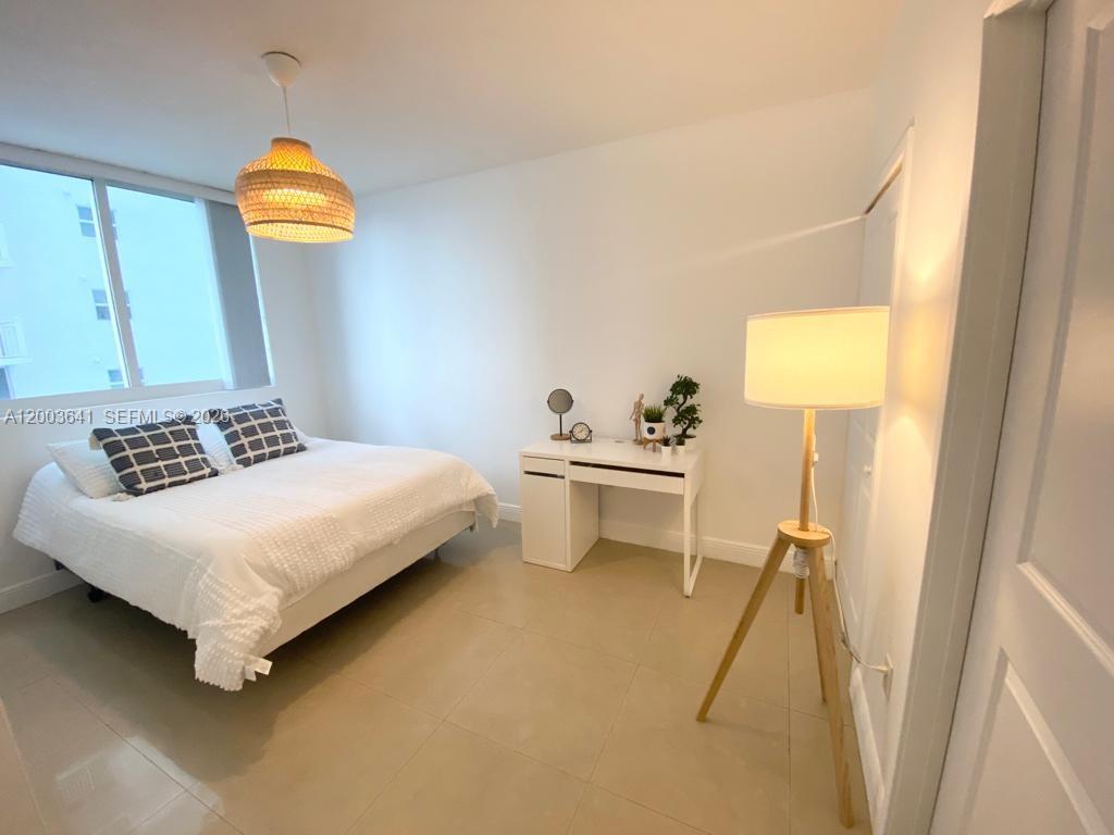 A bedroom features a bed, a white desk, a floor lamp, and a woven pendant light — 170 SE 14th St # 1504, Miami FL 33131, MIAMI, FL