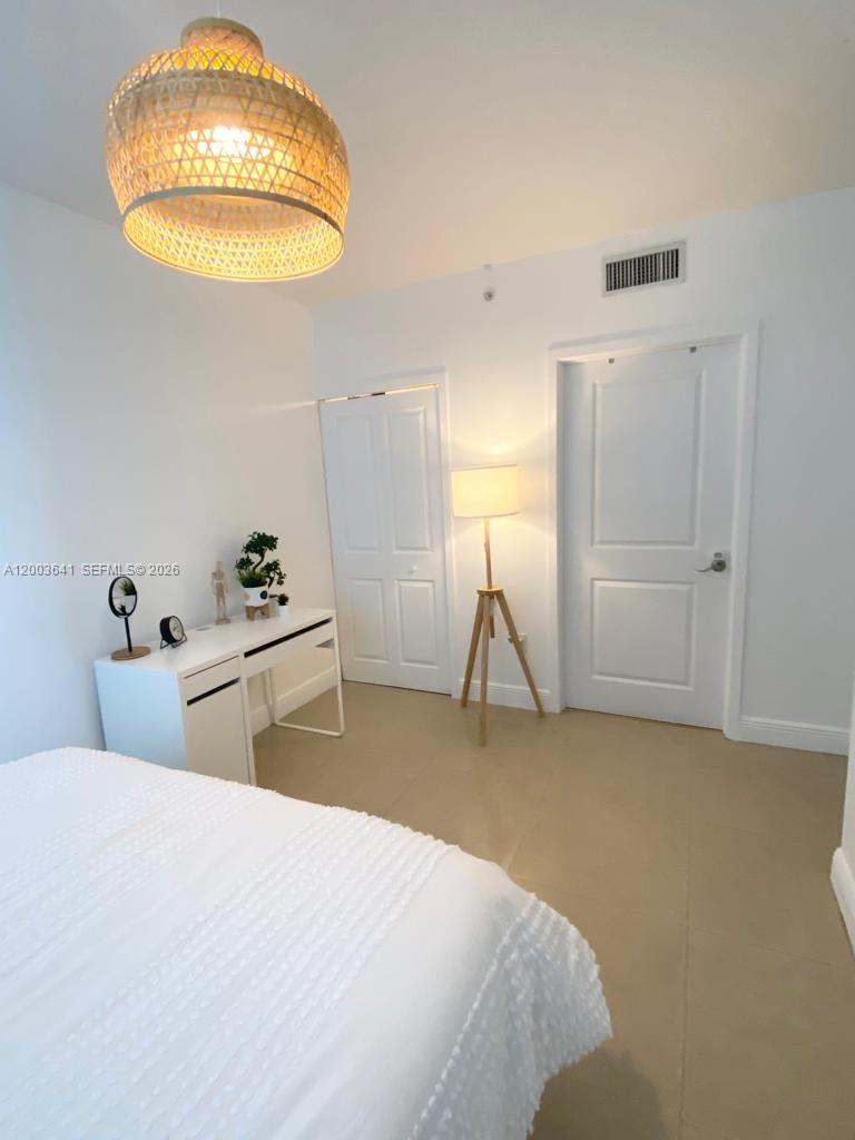 A bedroom features a white desk, a tripod floor lamp, and a woven pendant light — 170 SE 14th St # 1504, Miami FL 33131, MIAMI, FL