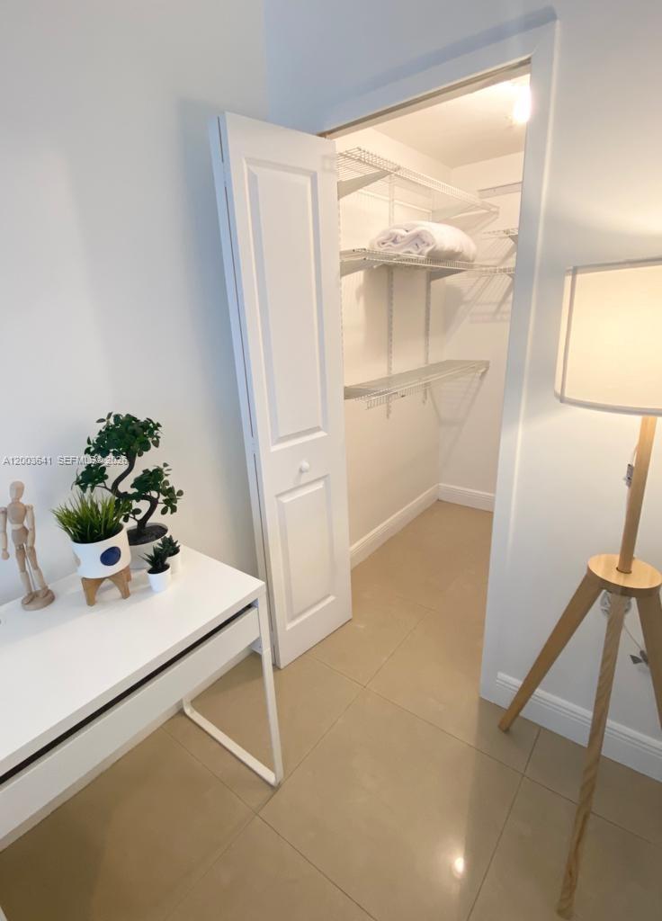 A white desk with potted plants sits next to a closet with wire shelving — 170 SE 14th St # 1504, Miami FL 33131, MIAMI, FL