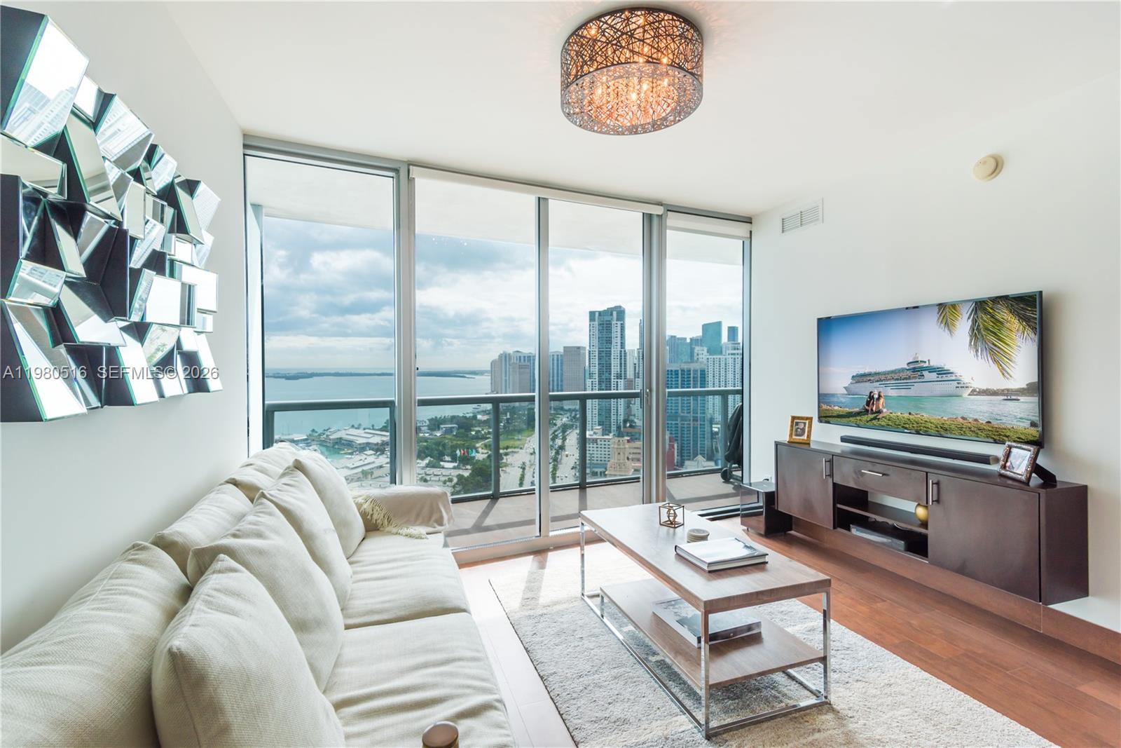 A modern living room features a white sofa, a wooden coffee table, and floor-to-ceiling windows — 888 Biscayne Blvd # 3506, Miami FL 33132, MIAMI, FL
