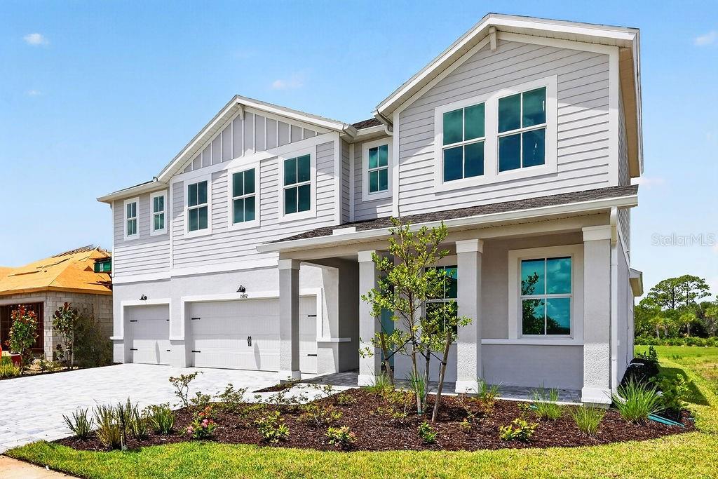 A two-story house with light gray siding, a two-car garage, and a landscaped front yard — 15692 ROSEBUD COURT, PUNTA GORDA, FL