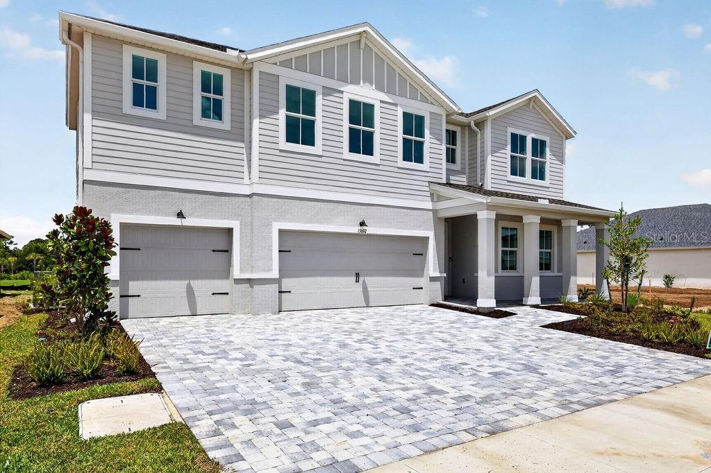 A two-story house with a gray exterior, a three-car garage, and a paved driveway — 15692 ROSEBUD COURT, PUNTA GORDA, FL