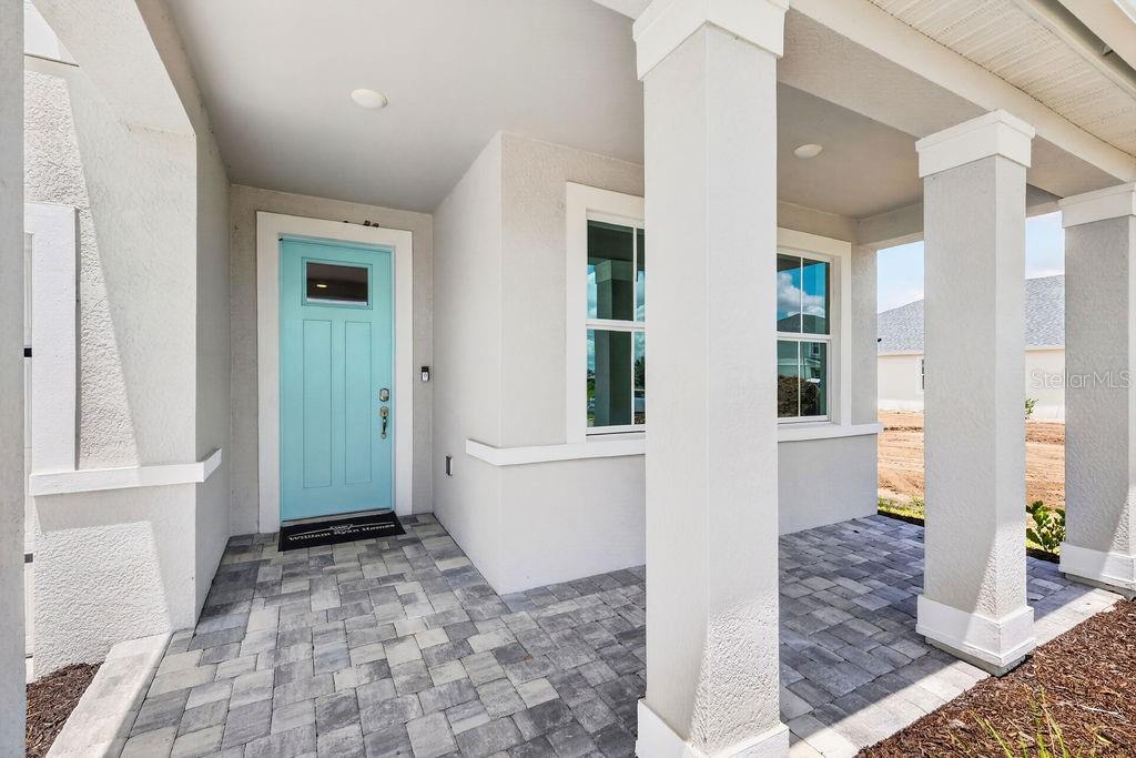 A light blue front door opens onto a covered porch with gray paver flooring — 15692 ROSEBUD COURT, PUNTA GORDA, FL