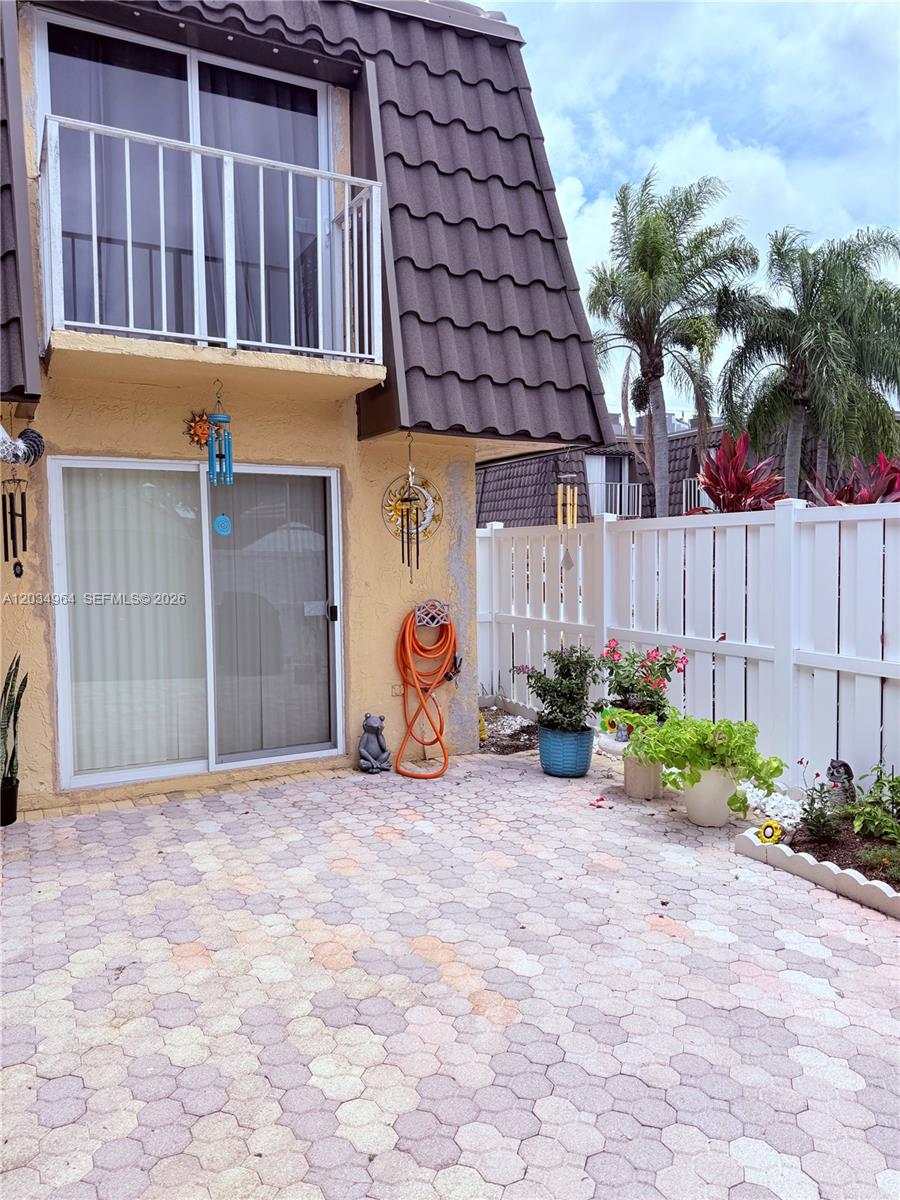 A paved patio sits outside a building with a balcony and a white fence — BOCA RATON, FL