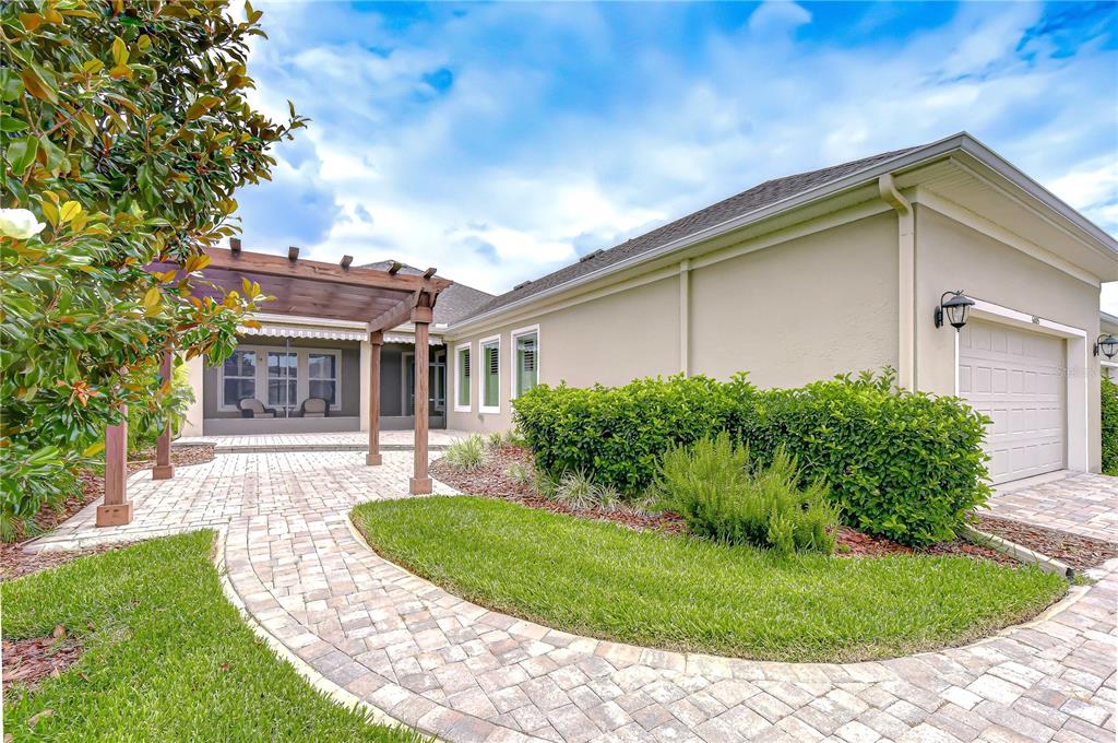 A paved walkway leads to a wooden pergola and a house with a garage — 6005 SPARROWHEAD WAY, LITHIA, FL