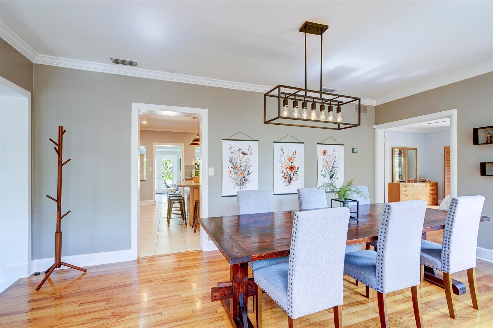 A dining room features a wooden table, upholstered chairs, a rectangular chandelier, and wall art — 411 26th Street, West Palm Beach FL 33407, WEST PALM BEACH, FL