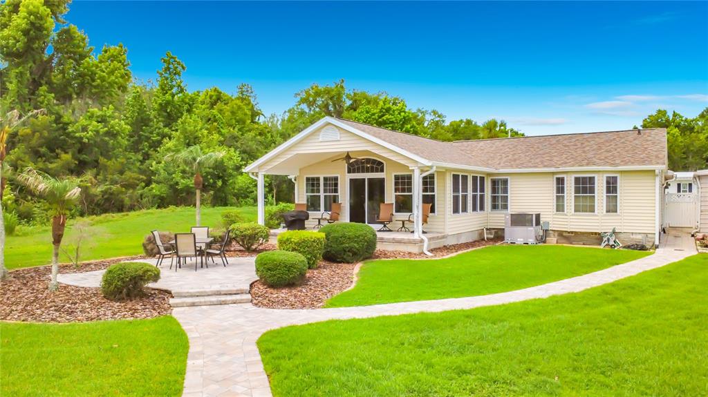A light yellow house with a covered patio, stone pavers, and a manicured lawn — 4703 CASSANDRA LANE, LAKELAND, FL