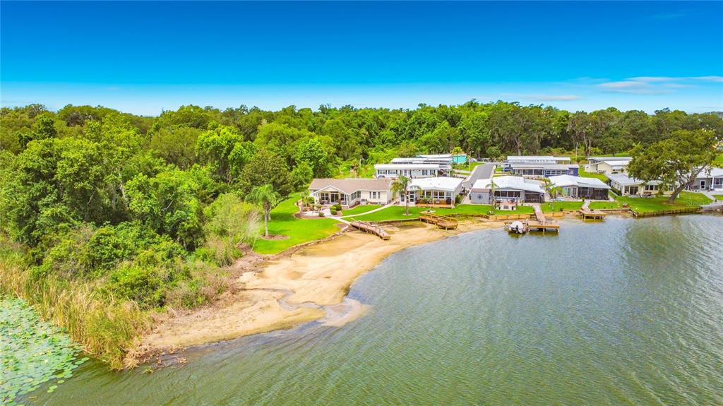 An aerial view shows several waterfront houses with private docks along a sandy shoreline — 4703 CASSANDRA LANE, LAKELAND, FL