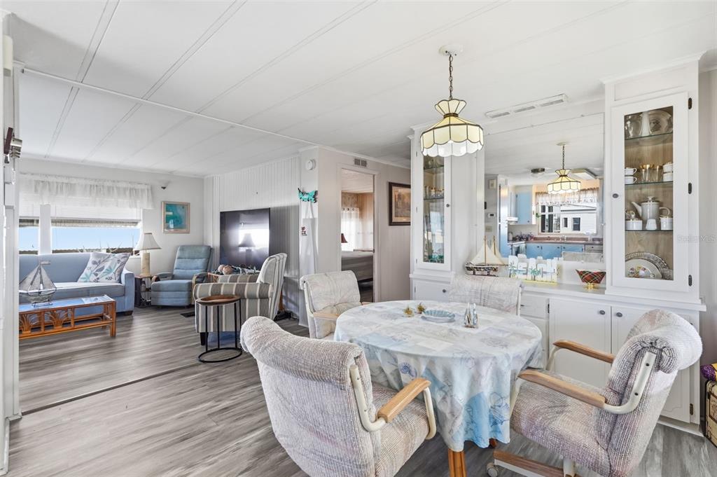A dining area with a round table and chairs sits adjacent to a living room — 82403 NEW CIRCLE DRIVE N, PINELLAS PARK, FL