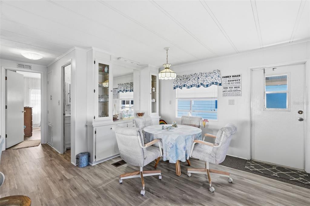 A dining area features a round table with four chairs, a built-in hutch, and wood-look flooring — 82403 NEW CIRCLE DRIVE N, PINELLAS PARK, FL