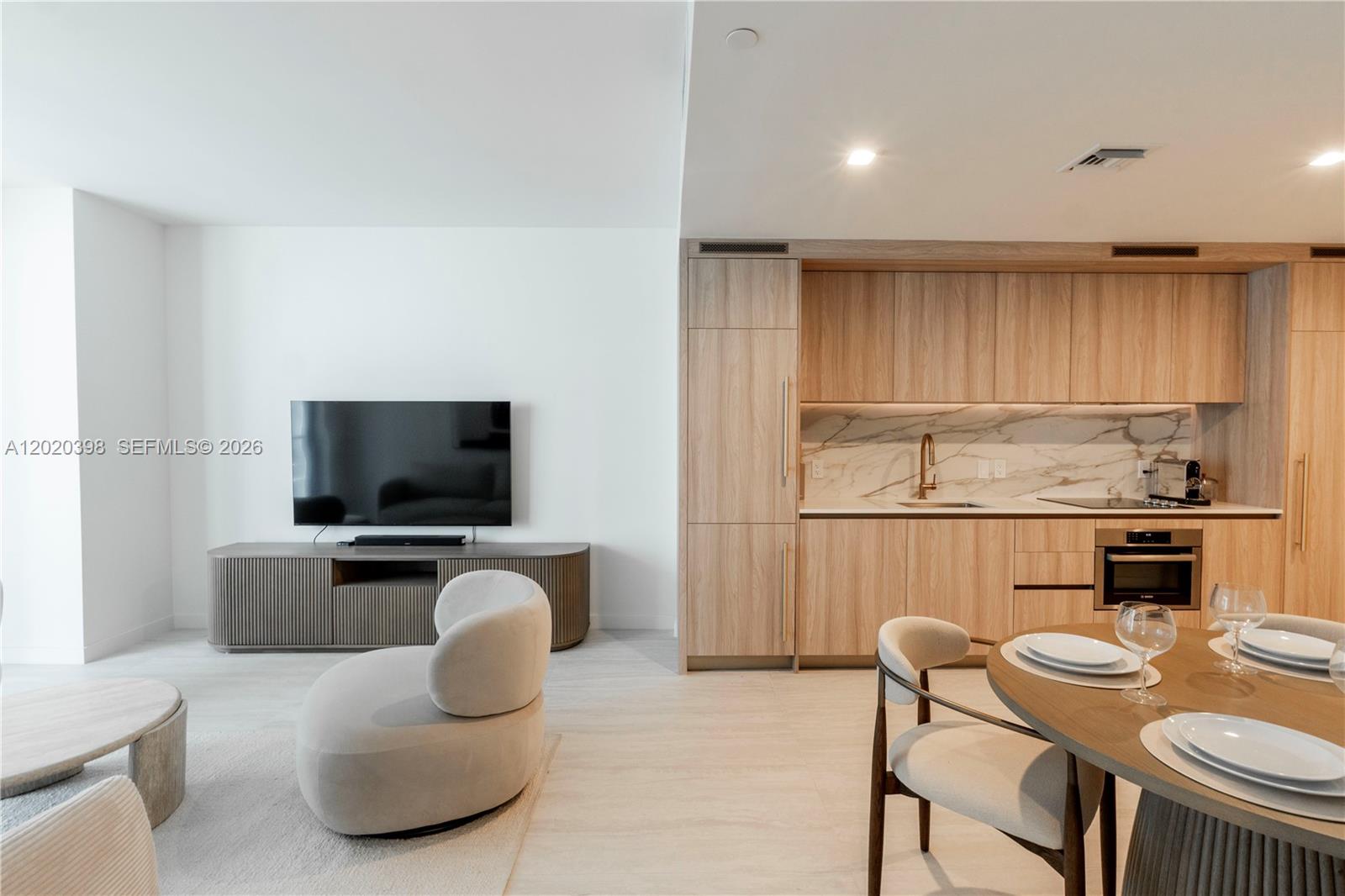 A modern open-concept living area features a kitchen with wood cabinetry and a dining space — 77 SE 5th St # 1910, Miami FL 33131, MIAMI, FL