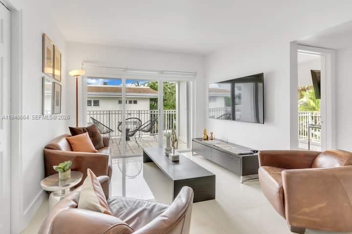 A modern living room features brown leather furniture, a long media console, and a balcony — 290 Sunrise # 206, Key Biscayne FL 33149, KEY BISCAYNE, FL