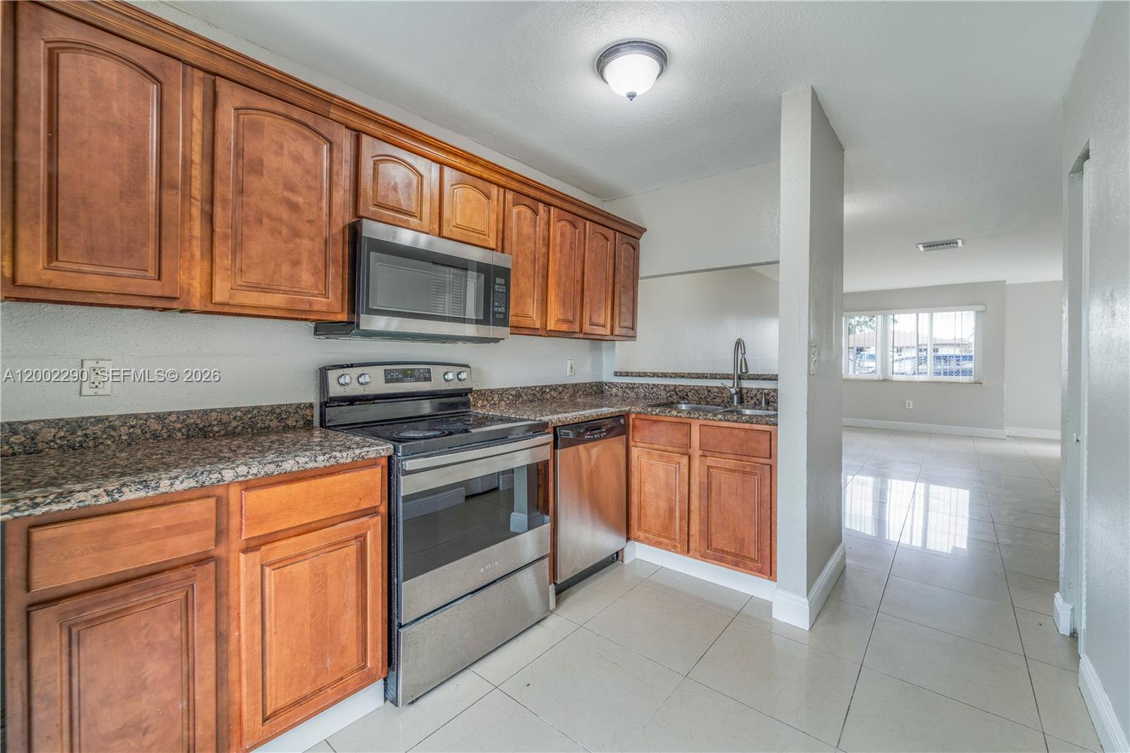A kitchen features wood cabinets, granite countertops, stainless steel appliances, and light tile flooring — 11310 SW 189th St # 11310, Miami FL 33157, MIAMI, FL