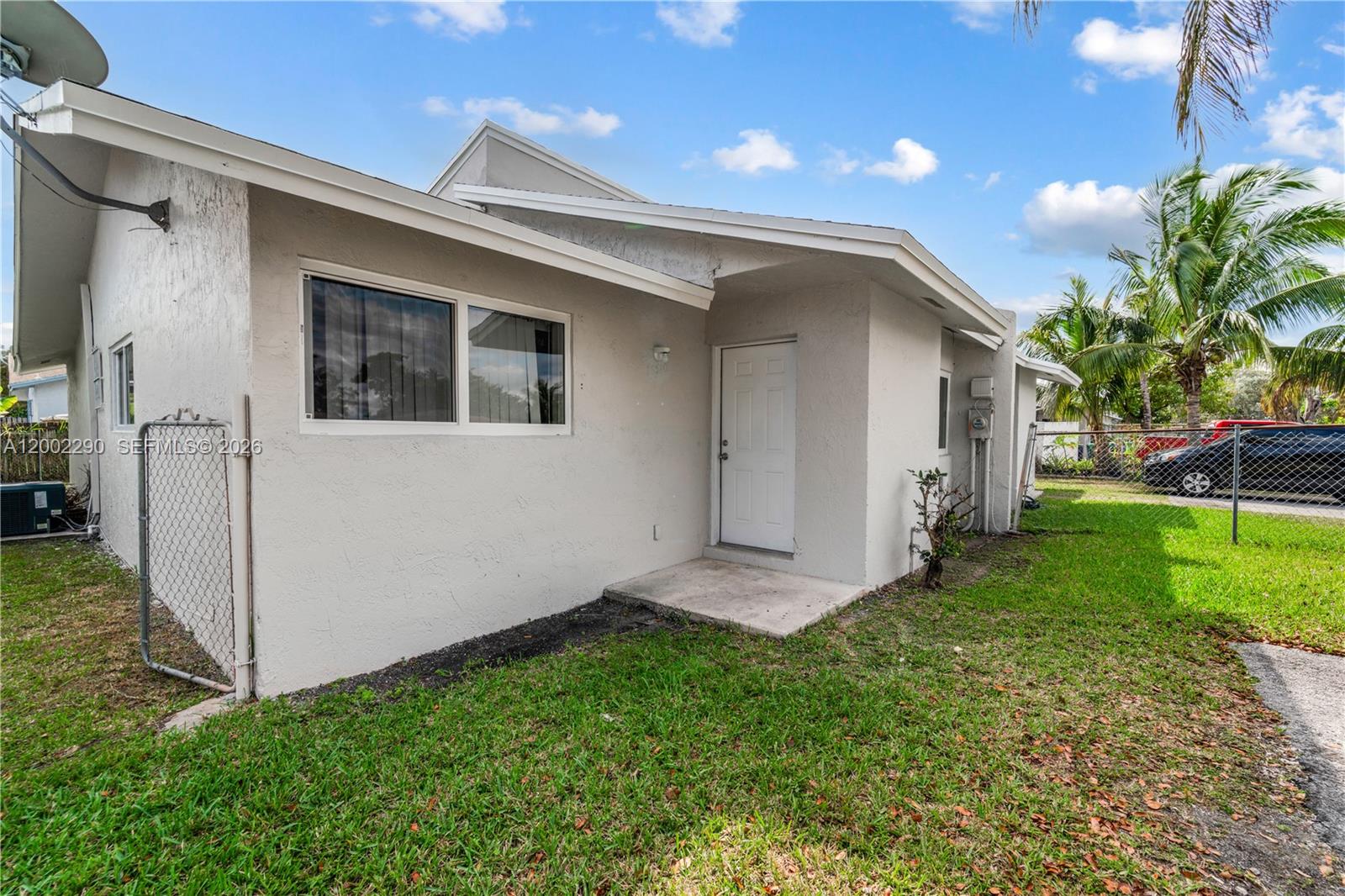 A side view of a single-story house with a white door and a chain-link fence — 11310 SW 189th St # 11310, Miami FL 33157, MIAMI, FL